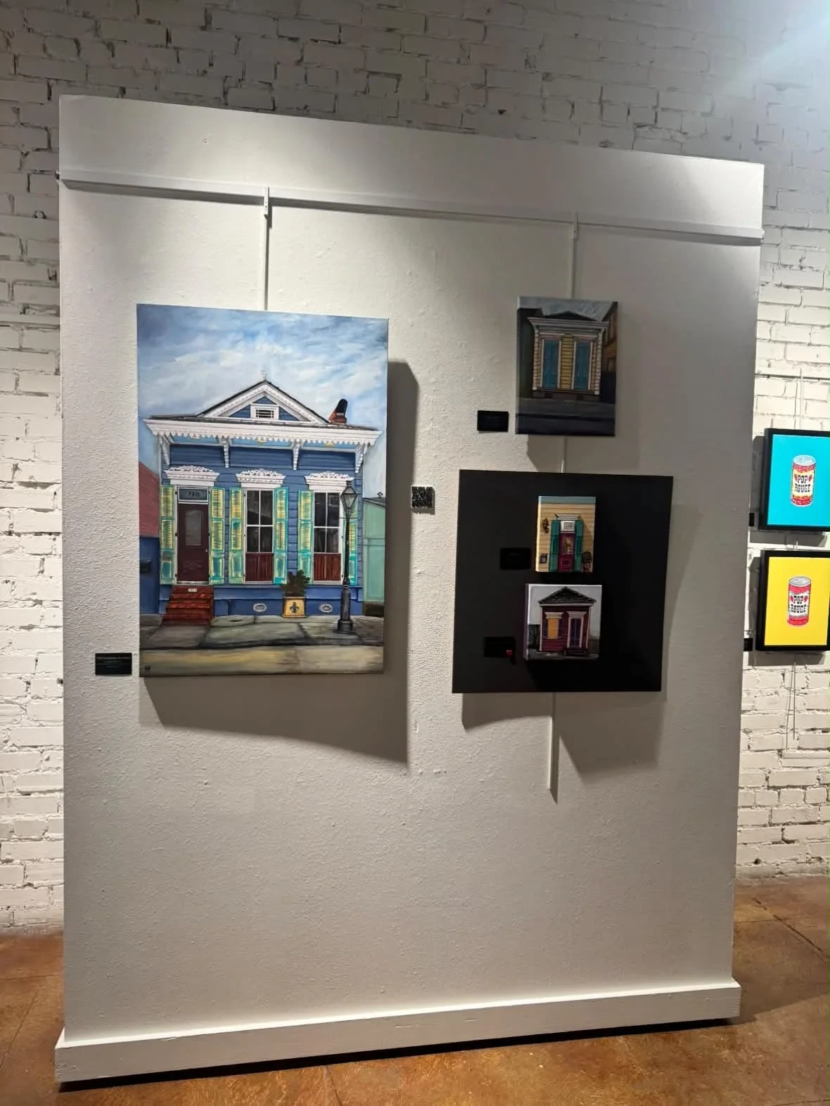 Paintings of colorful houses and architectural details on display.