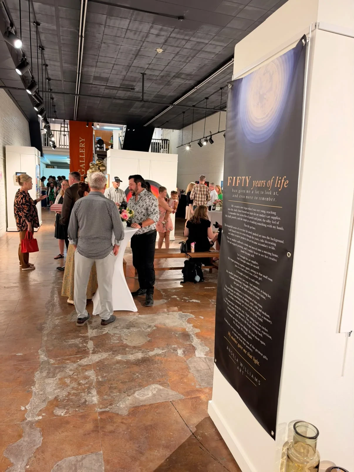 The exhibition statement beside guests gathered in the gallery.